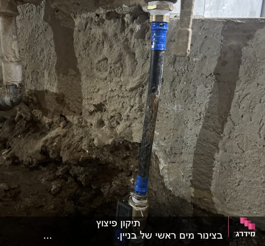 צינור מים עם ברז ומחברים על קיר בטון